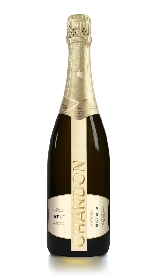A bottle of CHANDON Brut sparkling wine from Argentina, with a gold and white label, next to an elegant wine glass filled with clear, sparkling white wine, arranged against a modern, minimalist background of an abstract, textured gold panel.