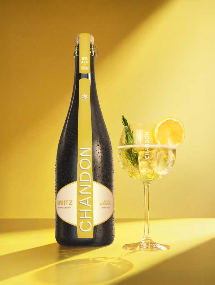 Une bouteille de Chandon Spritz Lemon & Verbena à côté d'un verre de cocktail Chandon Spritz garni d'une tranche de citron et d'un brin de romarin.