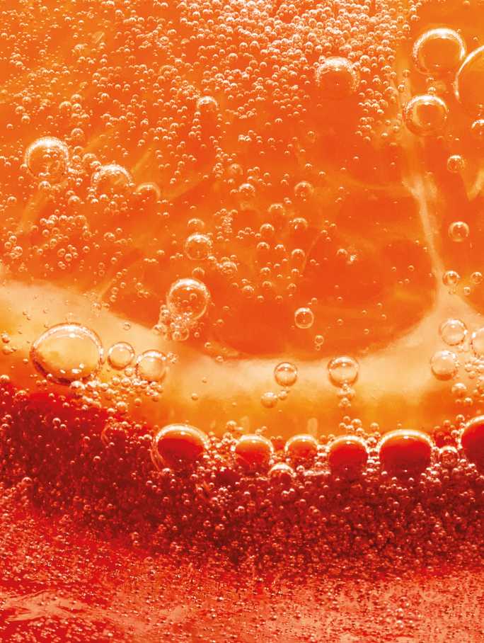 Gros plan d'une tranche d'orange immergée dans un liquide pétillant, de couleur orangée