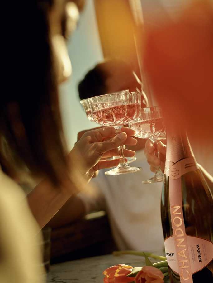 Two people cheering with two glasses of CHANDON Rosé