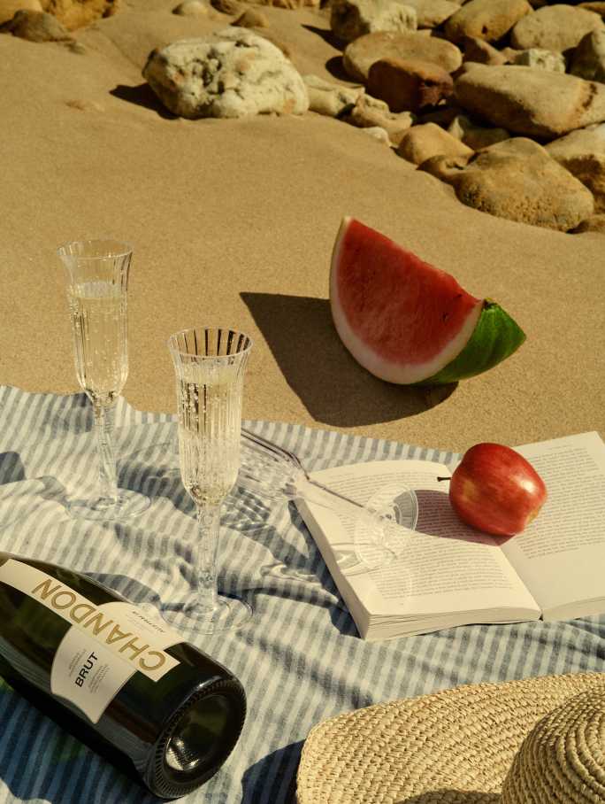 CHANDON BRUT with two glasses on a towel on the beach in sunny weather